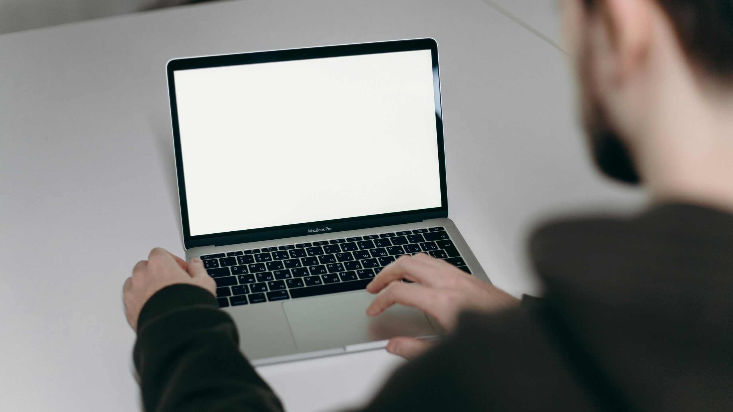 A man typing on a laptop with a blank screen at home, illustrating remote work.